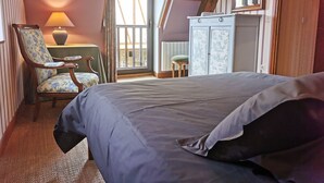 A bedroom with a bed, a chair, a lamp, a wardrobe, and a window. - Authentic Périgourdine house comfort & calm (Beynac-Et-Cazenac)