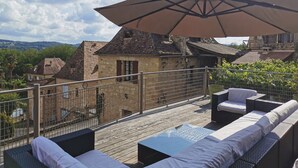 A rooftop terrace with outdoor seating and a large umbrella. - Authentic Périgourdine house comfort & calm (Beynac-Et-Cazenac)