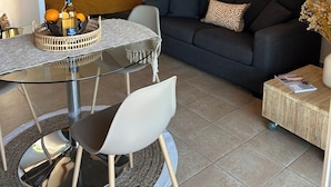 Een moderne woonkamer met een glazen eettafel, een bank en een bijzettafeltje.