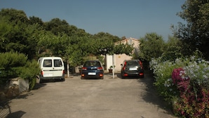 Een parkeerplaats met drie geparkeerde auto's voor een gebouw, omringd door groen.