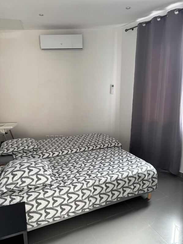 Ein Schlafzimmer mit Bett, Schreibtisch und einem Fenster mit Vorhängen.