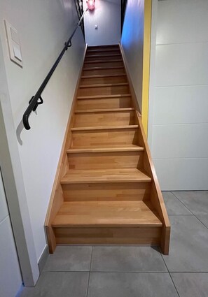 Stairs lead to an upper floor with a yellow accent wall.