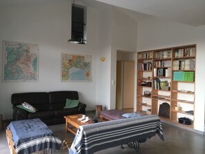 A living room with a sofa, a coffee table, a striped chair, a bookshelf, and two maps on the wall. - Detached house in village of character Ardèche. Garden, terrace, quiet location. (Saint-Maurice-D'ibie)
