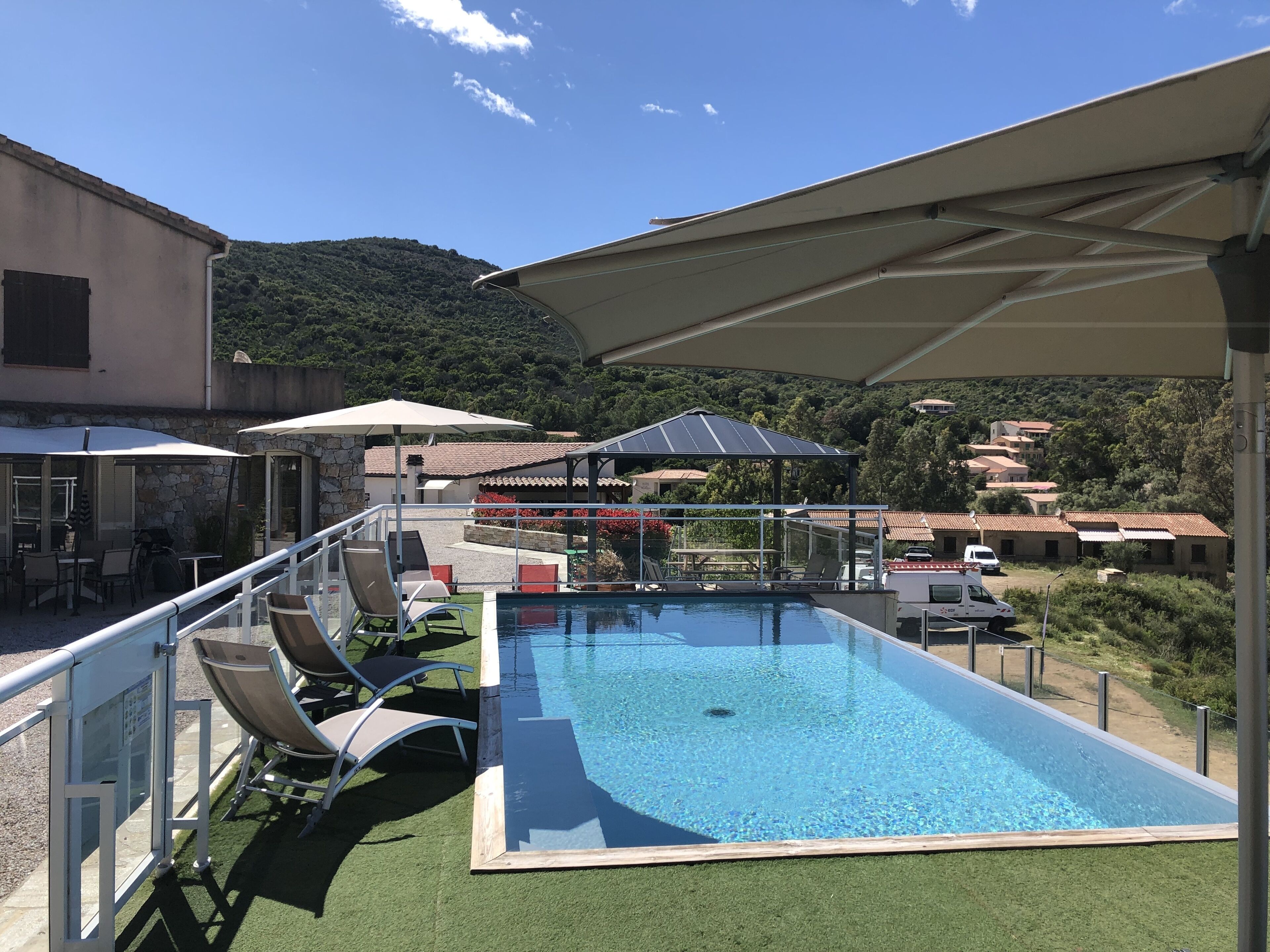 Une piscine sur le toit offrant une vue sur une colline et un village en arrière-plan.