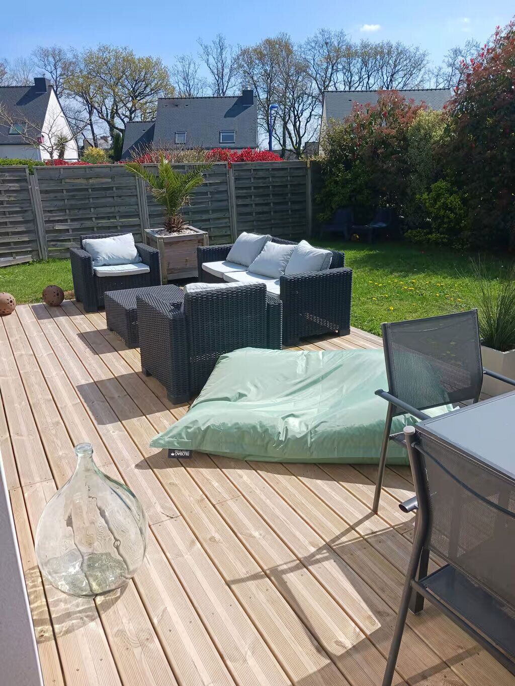 A deck with wicker furniture, a glass bottle, and a metal chair.