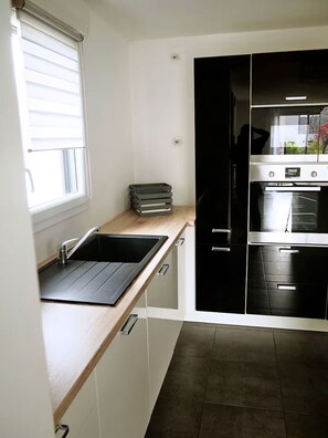 A kitchen with a sink, cabinets, and a stove.