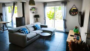 A modern living room with a sectional sofa, a round coffee table, a fireplace, and a dining area with a table and chairs.