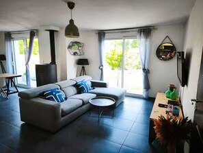 A modern living room with a sectional sofa, a round coffee table, a fireplace, and a dining area with a table and chairs.