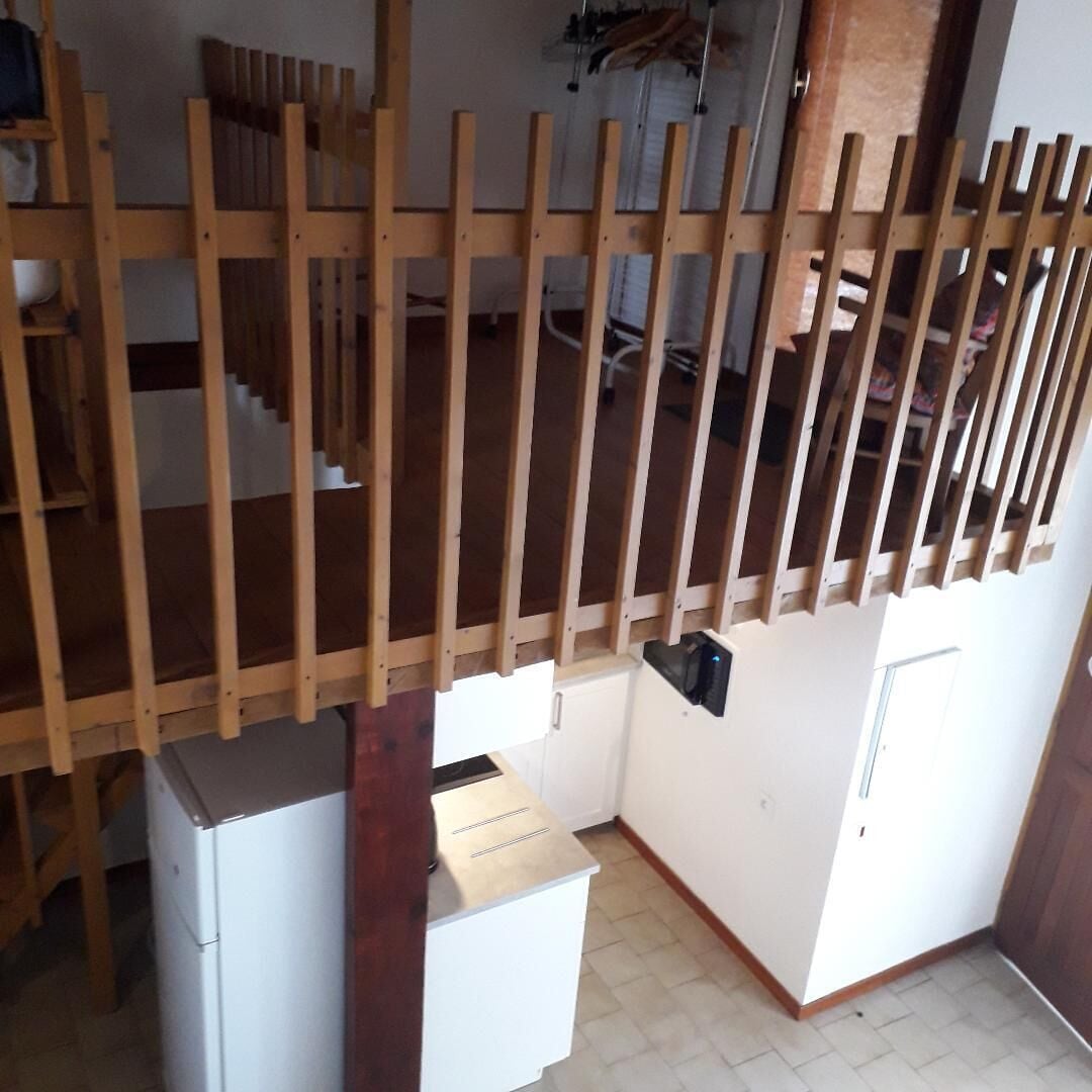 Una cocina compacta con refrigerador, una pequeña encimera y paneles de madera.