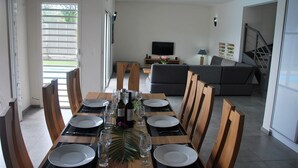 Un coin repas avec une table dressée pour six personnes, des chaises et un téléviseur en arrière-plan.