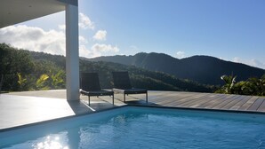 Un espace piscine avec deux chaises longues et une vue sur les montagnes.