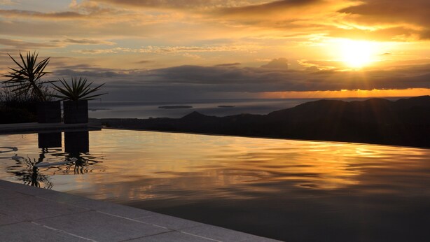 A serene infinity pool with a sunset view, surrounded by mountains and a calm body of water. - Spacious villa, oustanding views on sea and mountains, garden is 1600m2, 5**** (Les Adrets-De-L'estérel)