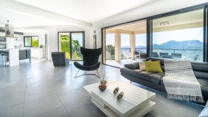 A modern living room with a sofa, coffee table, and a view of the outdoors. - Spacious villa, oustanding views on sea and mountains, garden is 1600m2, 5**** (Les Adrets-De-L'estérel)