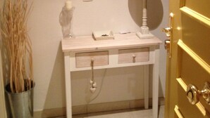 Ein Badezimmer mit weißem Waschtisch, einem Spiegel, einer Lampe und einem Mülleimer.