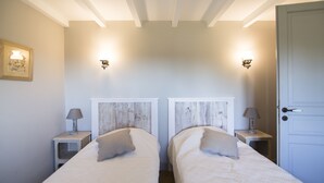 A twin bedroom with two beds, bedside lamps, and wall-mounted light fixtures.