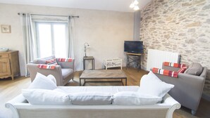 A cozy living room with a sofa, a coffee table, and a television.