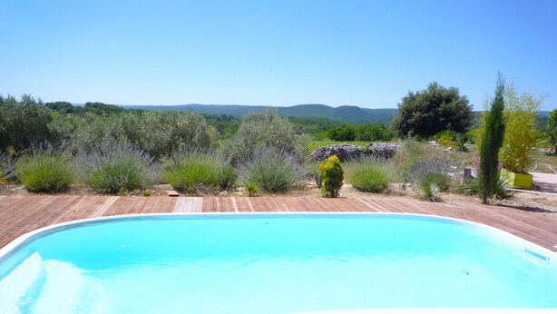 Un'area prendisole in legno che circonda una piscina rettangolare con acqua cristallina.