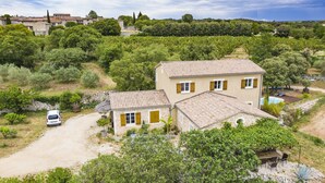 Una casa di campagna con un vialetto sterrato, immersa nel verde e circondata da vigneti.