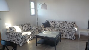 Un soggiorno con due divani decorati con motivi floreali, un tavolino in vetro, una lampada da terra e un piccolo tavolino di servizio.