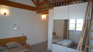 Una camera da letto con letto a soppalco, travi in legno, una scala e un grande specchio.