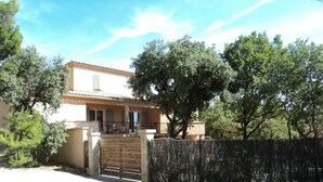 Una casa de dos pisos con techo de tejas, puerta de madera y camino de entrada de grava.