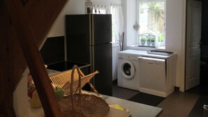 Une cuisine équipée d’un lave-linge, d’un réfrigérateur et d’une fenêtre avec des rideaux.
