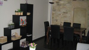 Un salon chaleureux avec une table en bois foncé, un canapé blanc et un coin repas agrémenté d’un mur en pierre et d’une cheminée.