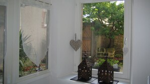 Une pièce avec une fenêtre donnant sur un jardin, une petite étagère avec deux lanternes décoratives et un décor en forme de cœur sur le mur.