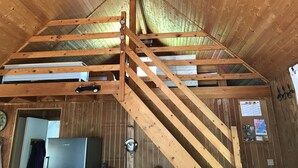 Un intérieur en bois avec un escalier apparent, un réfrigérateur et un tableau d’affichage.