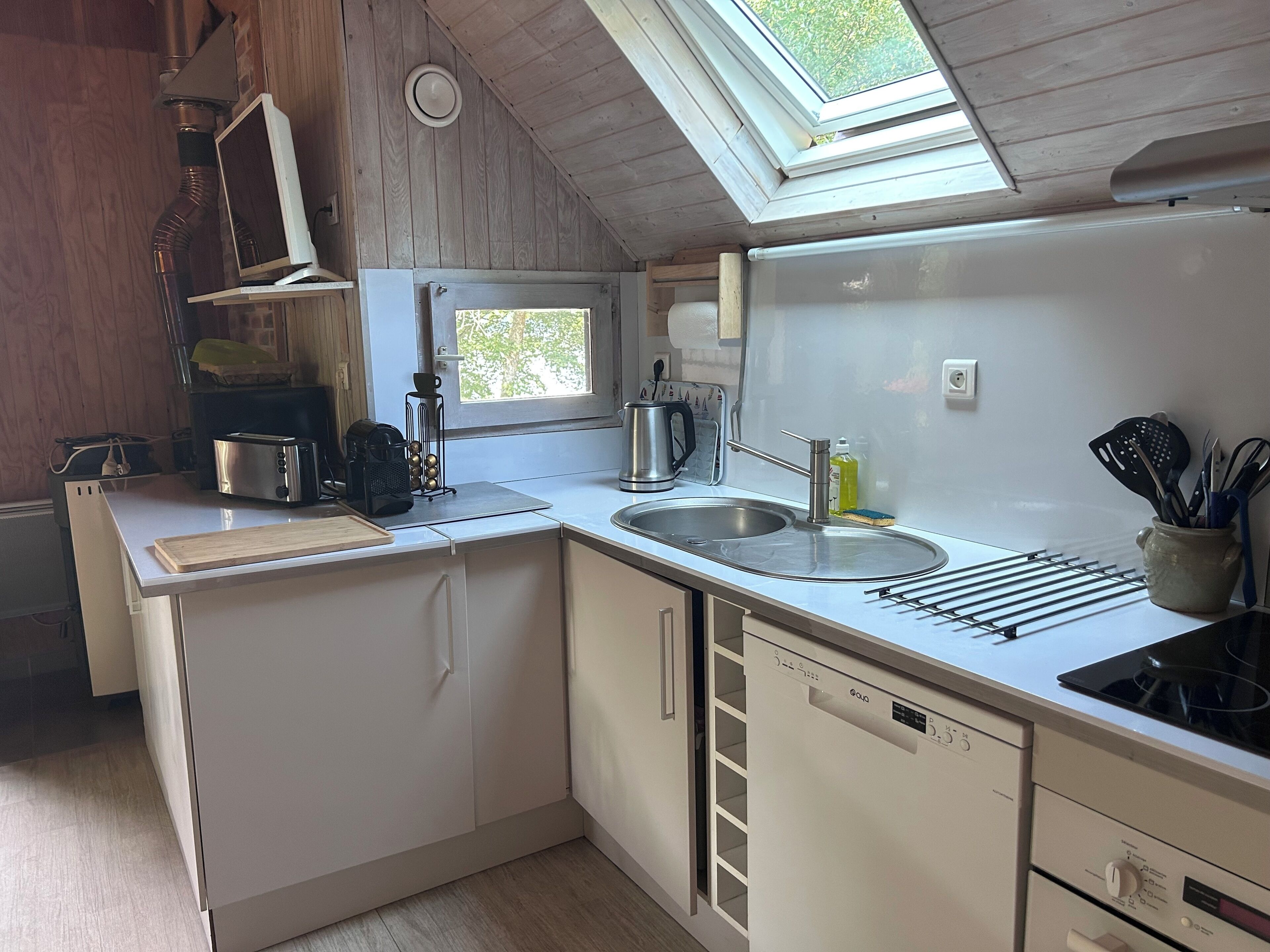 Een kleine keuken met dakraam, een spoelbak, een broodrooster en een koffiezetapparaat.