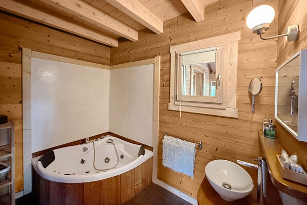 A wooden cabin bathroom with a bathtub, sink, and a mirror.