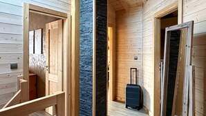 Un intérieur en bois avec un mur d’accent en pierre, un escalier en bois et une valise dans le couloir.