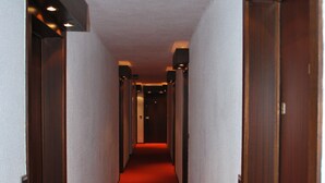 Un pasillo con alfombra roja, puertas de madera e iluminación empotrada.