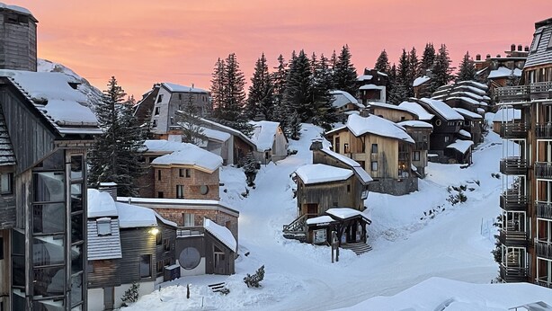A snow-covered village with wooden buildings and a ski slope. - Charming Studio 4 pers with south balcony and mountain view (Morzine)