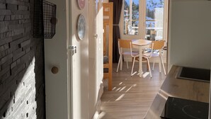 A modern kitchen with a wooden countertop and a built-in stove. There is a dining area with a table and chairs, and a view of a snowy mountain through the window. - Charming Studio 4 pers with south balcony and mountain view (Morzine)