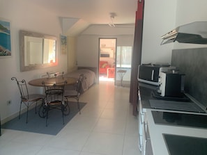 A modern kitchen with a microwave, coffee maker, and a dining area with a table and chairs. - BEAUTIFUL air-conditioned T2 60m2 100 m from Les Lecques beach + parking lot (Saint-Cyr-Sur-Mer)
