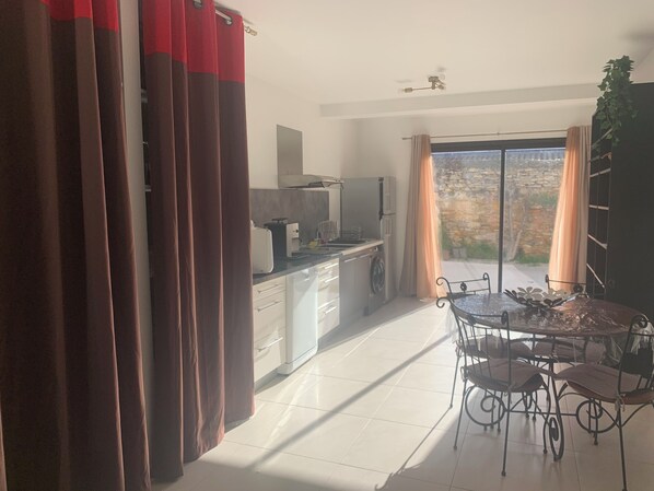 Una cocina moderna con comedor, ventilador de techo y vista a una pared de piedra.