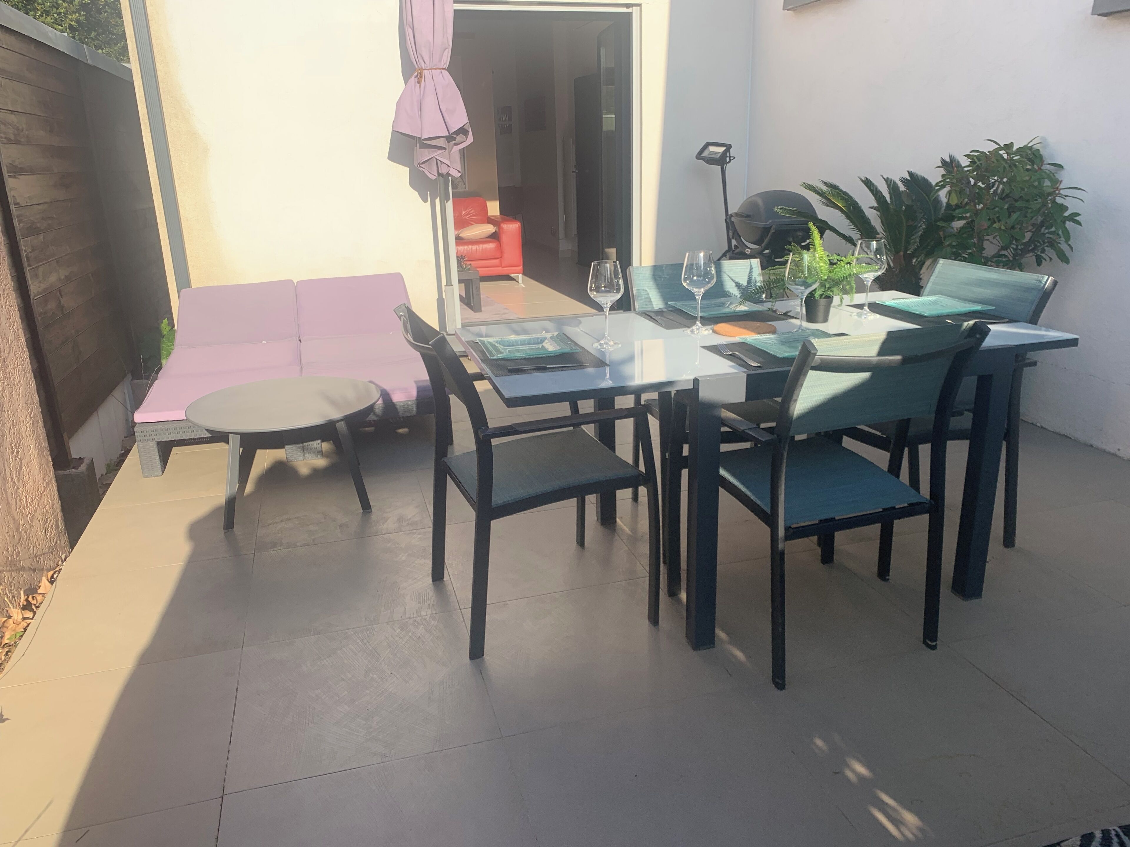 Een terras met een tafel, stoelen, een rode bank en een bloempot.