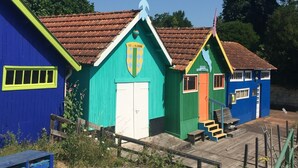 Een rij kleurrijke houten gebouwen met pannendaken, een witte deur en een bord waarop 'ILE OLERON' staat.