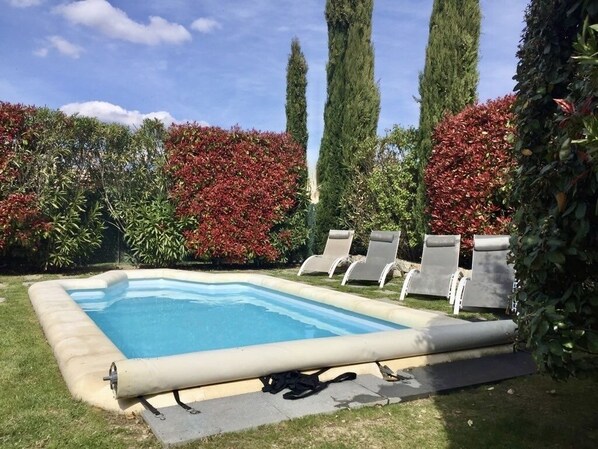 A rectangular swimming pool with a pool cover, surrounded by a grassy area and red foliage. - L'OUSTAOU WITH PRIVATE POOL (COLONZELLE)