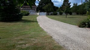 A gravel path leading to a gated entrance, surrounded by well-maintained grass and trees.