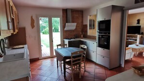 A compact kitchen with a dining area, a double door leading outside, and a small seating area.