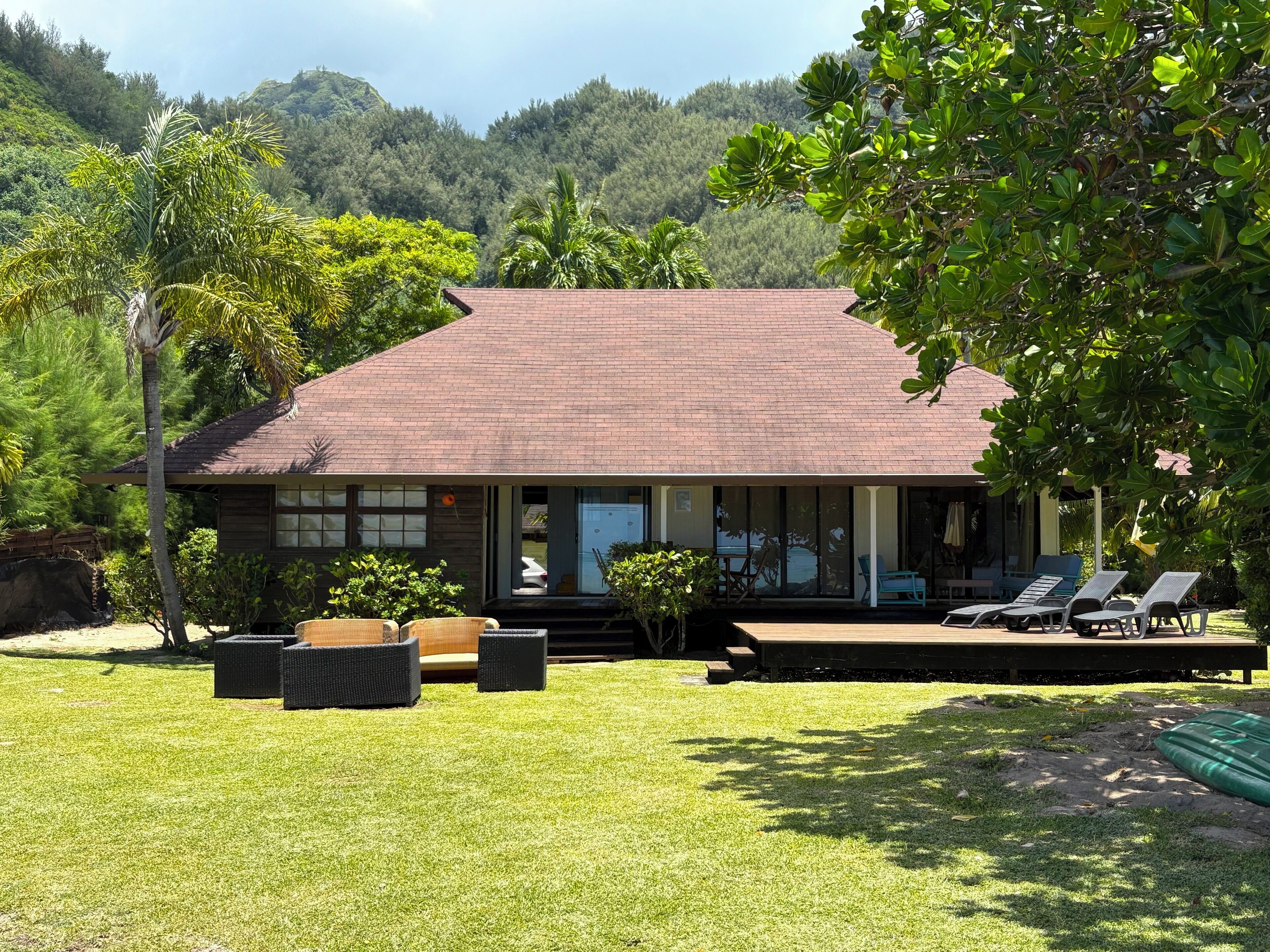 A two-story building with a brick roof and large windows. There is a patio area with lounge chairs and a small pool.