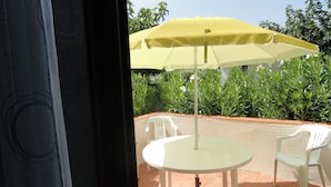 An outdoor patio with a yellow umbrella, white chairs, and a round table. - GROUND FLOOR DIRECT ACCESS BEACH 'uncrowded' Gde Terrace (Le Barcarès)