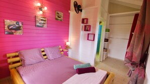 A room with a bed, a wall-mounted fan, and a door leading to another room.