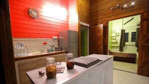 A kitchen with a wooden countertop, a refrigerator, and a clock on the wall.
