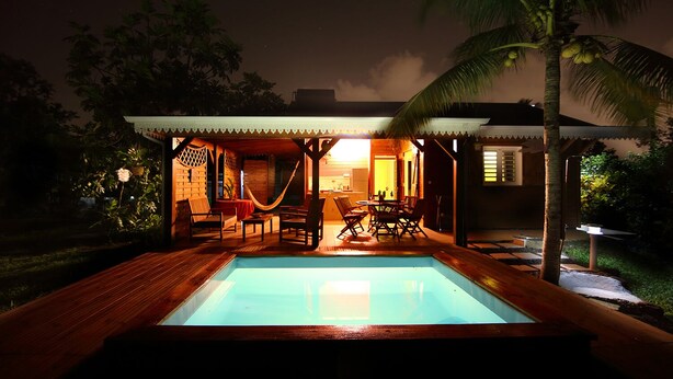 A poolside area with wooden decking, a hammock, and outdoor seating.
