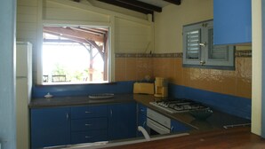 A kitchen with blue cabinets, a window, a stove, and a sink.