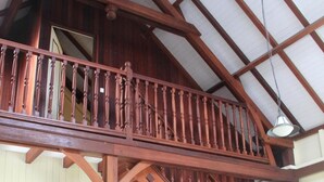 A wooden staircase with a balcony, a wicker chair, and a ceiling fan.