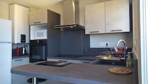 Una cocina moderna con una isla central, horno empotrado, microondas y campana extractora de acero inoxidable.